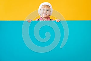 Happy child holding blue Christmas banner blank against yellow background