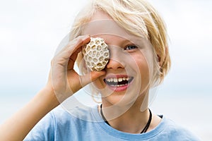 Happy child holding coral over his eye