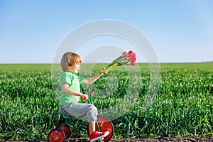 Happy child holding flowers against blue sky background