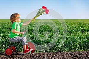 Happy child holding flowers against blue sky background