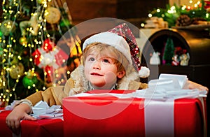 Happy child holding a giant red gift box with both hands. Christmas kids. New year kids. Funny kid holding Christmas
