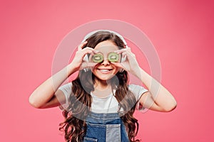 Happy child holding kiwi fruit over eyes isolated