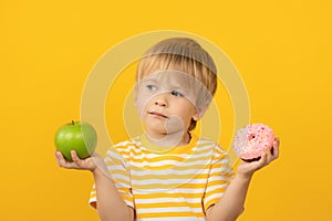 Happy child holding pink donut and green apple