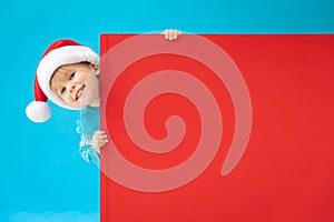 Happy child holding red Christmas banner blank against blue background