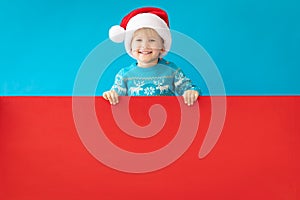 Happy child holding red Christmas banner blank against blue background