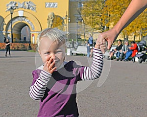 Happy child holds mother`s hand on walk