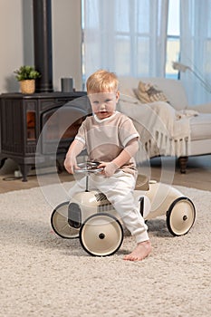 Happy child at home. Little toddler boy driving big vintage toy car and having fun. Smiling kid playing at home. Baby