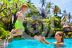 Happy child jump to mother hands in swimming pool