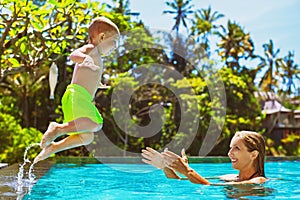 Happy child jump to mother hands in swimming pool