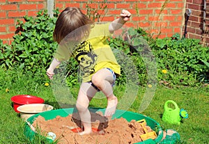Happy child jumping in a sand pit.