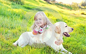 Happy child and labrador retriever dog lying on grass