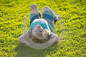 Happy child laying upside down on green grass in summer Park. The concept of a healthy lifestyle. The fun and carefree