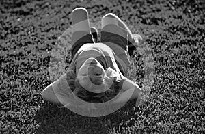 Happy child laying upside down on green grass in summer Park. The concept of a healthy lifestyle. The fun and carefree