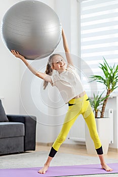 Happy Child Lifting Exercise Ball Above Head