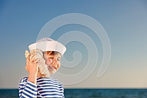 Happy child listen seashell on the beach