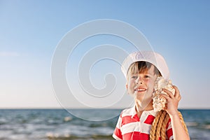 Happy child listen seashell on the beach