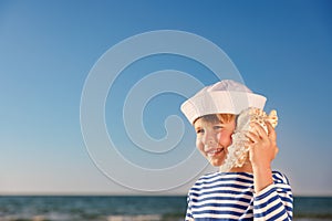 Happy child listen seashell on the beach