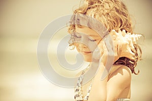 Happy child listen to seashell at the beach