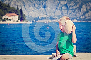 Happy child listening seashell at the beach