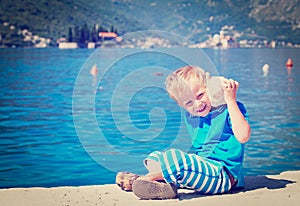 Happy child listening seashell at the beach