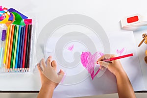 Happy child little girl colorful drawing pink heart on white paper