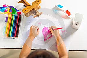 Happy child little girl colorful drawing pink heart on white paper