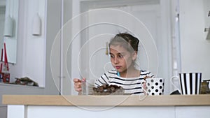 Happy child little girl eat date fruit in the summer home kitchen.