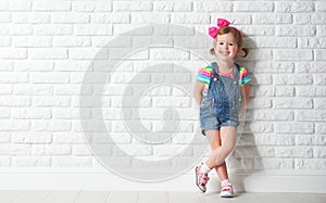 Happy child little girl laughing at blank brick wall