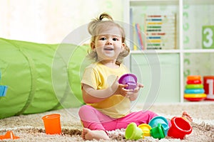 Happy child little girl playing with toys indoors