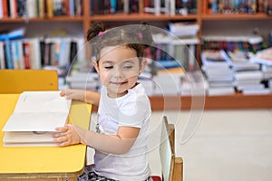 Happy child little girl reading a book.