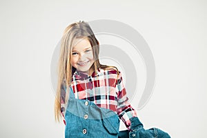 Happy child. the little girl is smiling cheerfully. kids fashion in a denim jacket and a sleeved shirt. gray background. studio