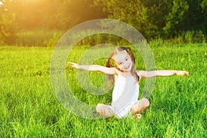 Happy child little girl spread his arms in white dress lying on