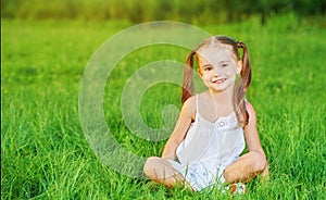 Happy child little girl in white dress lying on grass Summer