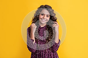 happy child with long brunette frizz hair on yellow background