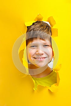Happy child looks into the camera lens on a yellow background photo