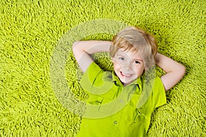 Happy child lying on the green carpet background