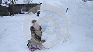 Happy child make a snowman outdoors.