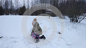 Happy child make a snowman in a snow-covered field