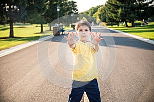 Happy child making a stop sign with his hand while standing at the road