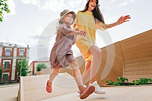 Happy child with mother running on the city park