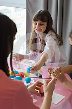 Happy child paints Easter eggs with his family
