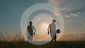 Happy child in the park plays with a soccer ball. Dream of childhood. Silhouette of a child with a soccer ball. Dream of