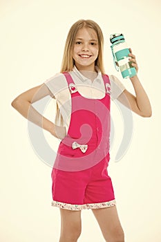 Happy child in pink jumpsuit hold water bottle. Little girl smile with plastic bottle isolated on white. Drinking water