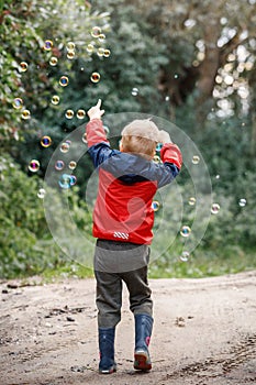 Happy child play with bubbles outdoor, selective focus - kid in motion