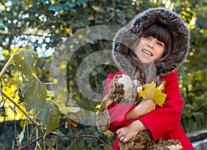 Happy child playing in autumn park. Kid gathering yellow fall foliage.