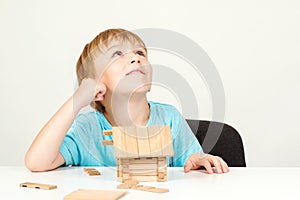 Happy child playing and building wooden home. Childhood dreams. Little boy builds his dream house. Happy life, house or mortgage