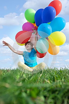 Happy child playing with colorful toy balloons outdoors