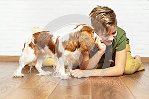 Happy child playing and embracing his puppy indoor. Teen boy with his puppy. Best friend and pet. Lovely dog. Kid and