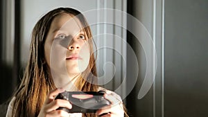 A happy child is playing on a game console, a teenage girl is holding a game joystick