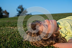 Happy child playing on green grass. Kids dreaming. Funny kid outdoor in spring garden. Children day. Happy carefree